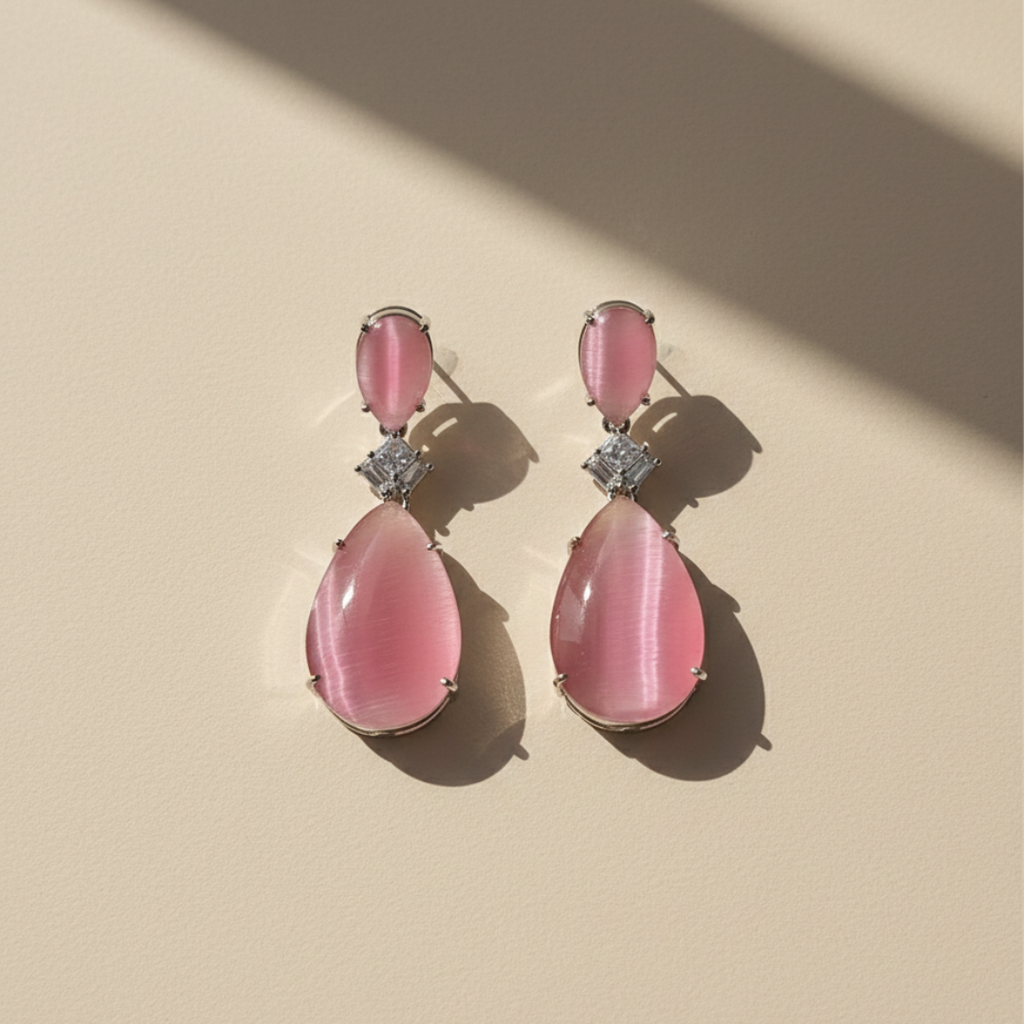 Blush pink zircon teardrop earrings with diamond-cut accent on soft beige background