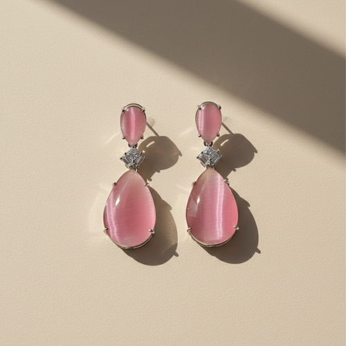 Blush pink zircon teardrop earrings with diamond-cut accent on soft beige background