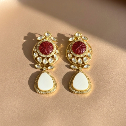 Gold-plated earrings featuring kundan stones, red carved center, and white mother of pearl teardrop, displayed on nude satin fabric without back clips
