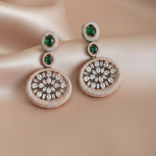 Round statement earrings with green oval stones and American diamond floral center, set in a silver halo, displayed on a nude satin background.