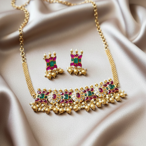 Traditional brass choker necklace with micro gold plating featuring pink and green stones, paired with matching earrings on a satin background.